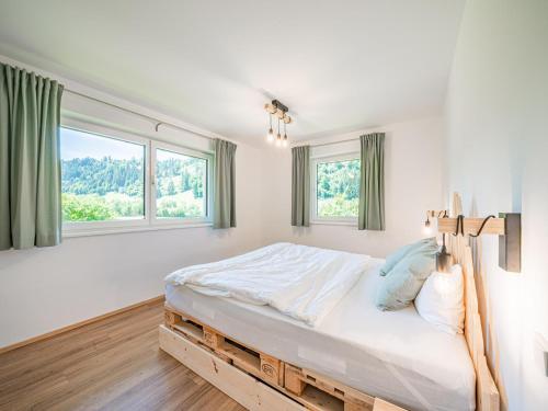 a white bedroom with a large bed and windows at Tirola Bude Sepp Top 4 in Hopfgarten im Brixental