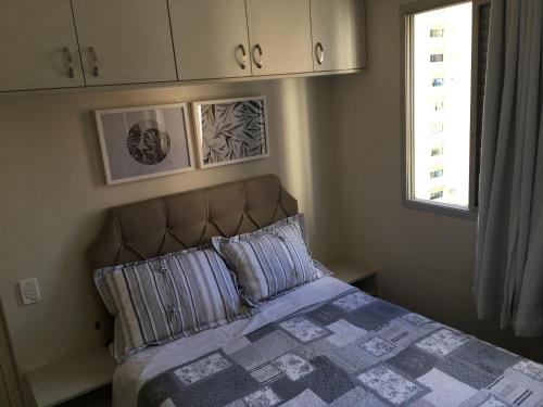 a bedroom with a bed with two pillows and a window at Apartamento João e Maria, no coração do Cambuí in Campinas