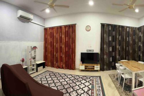 a living room with a table and a television and a table and chairs at Azzahra Homestay Pekan with 3 Bedrooms fully airconditioner in Pekan