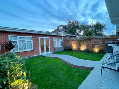 a backyard with a brick house and a lawn at Brand New Modern Flat in Southall