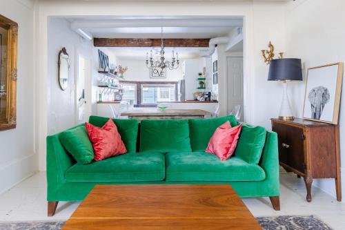 a green couch with red pillows in a living room at Boutique Apartment in 1905 Victorian Home - Plaza - Westport in Kansas City