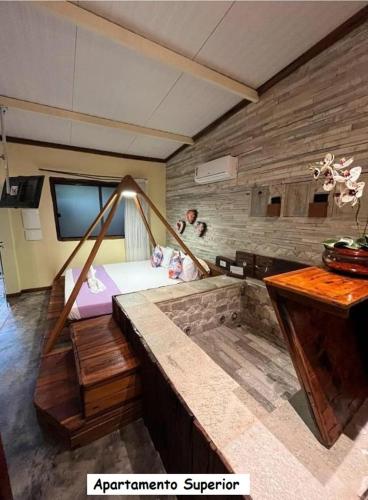 a room with a stone wall and a tv at Sanctuary Pirenópolis Suítes e Flats in Pirenópolis