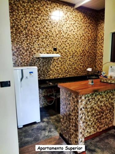 a kitchen with a refrigerator and a wall covered in logs at Sanctuary Pirenópolis Suítes e Flats in Pirenópolis