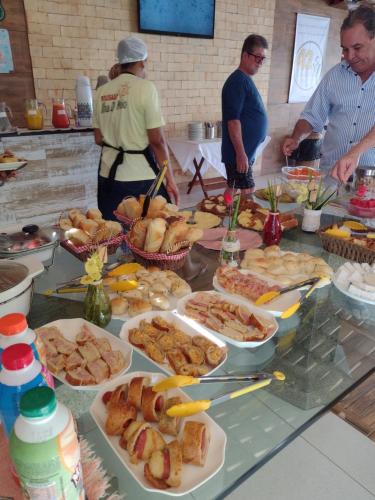 a group of people standing around a table with food at Pousada Ilha do Meio in Itacimirim