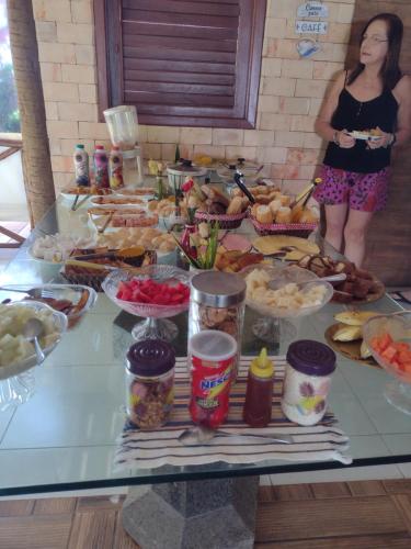 a woman standing in front of a table full of food at Pousada Ilha do Meio in Itacimirim