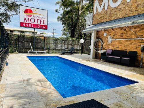 a swimming pool in front of a building with a motel sign at Port Stephens Motel in Nelson Bay