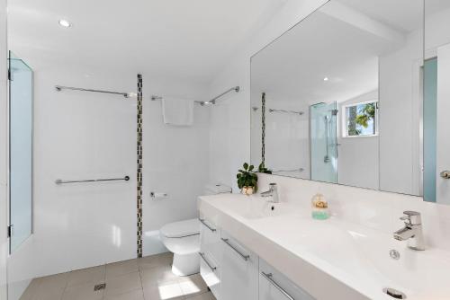 a white bathroom with a toilet and a sink at 12 Coco Bay in Noosaville