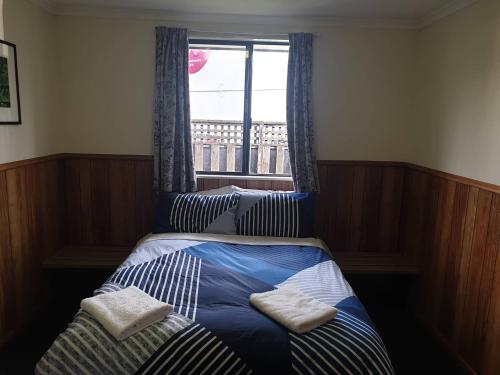 a bedroom with a bed with two pillows and a window at Wilderness Backpackers in Haast