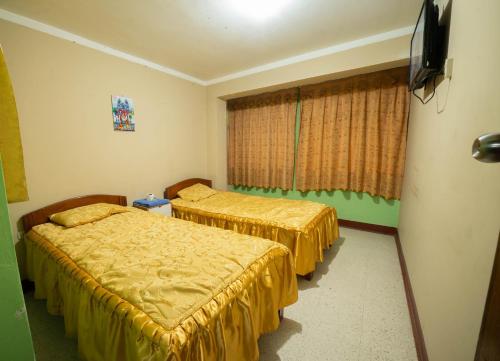 a hotel room with two beds and a window at HOSTAL TARAPACA in Huánuco