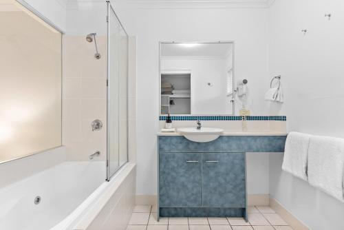 La salle de bains est pourvue d'un lavabo, d'une baignoire et d'un miroir. dans l'établissement North Facing, 2 bedroom Townhouse in Tropical Resort, à Noosaville
