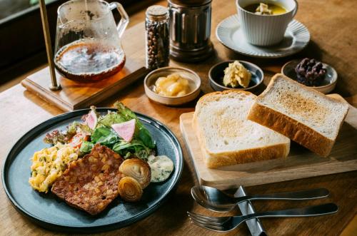 een houten tafel met een bord eten en brood bij Sabino House Kyoto in Kyoto