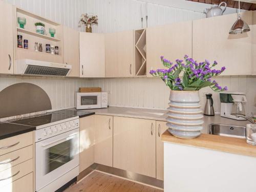 a kitchen with white cabinets and purple flowers in a vase at 4 person holiday home in Oksbøl-By Traum in Oksbøl