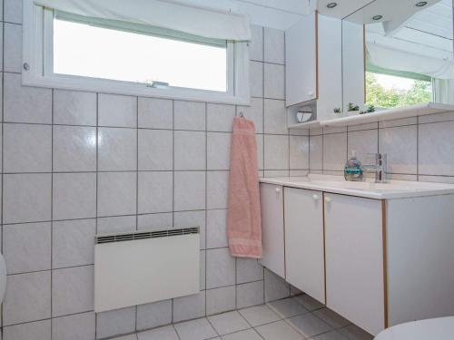 ein weiß gefliestes Bad mit einem Waschbecken und einem Fenster in der Unterkunft Holiday home Oksbøl LXXXIV in Oksbøl