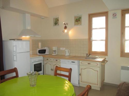 uma cozinha com uma mesa verde e um frigorífico branco em Gîte Dompierre-sur-Besbre, 3 pièces, 4 personnes - FR-1-489-174 em Dompierre-sur-Besbre