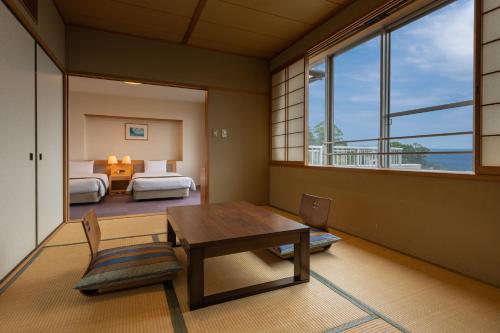 a room with a table and a bedroom with two beds at KAMENOI HOTEL Atami Annex in Atami