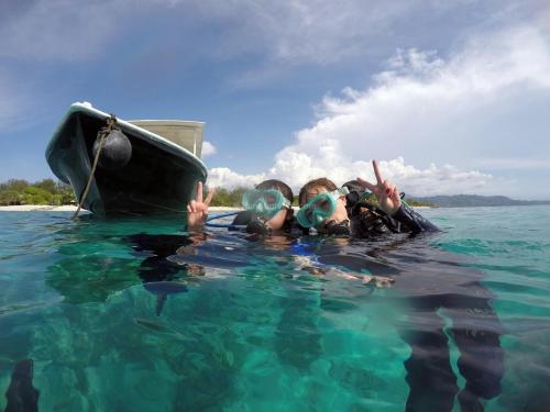 two people in the water next to a boat at Anema Wellness & Resort Gili Lombok - Diving Center PADI in Tanjung