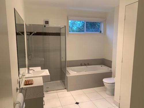 a bathroom with a tub and a toilet and a sink at Broadbeach Inverloch in Inverloch