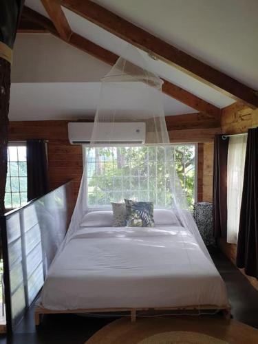 a large bed in a room with a window at CAMP TREEHOUSE • COTTAGE • POOL • JACUZZI in Antipolo