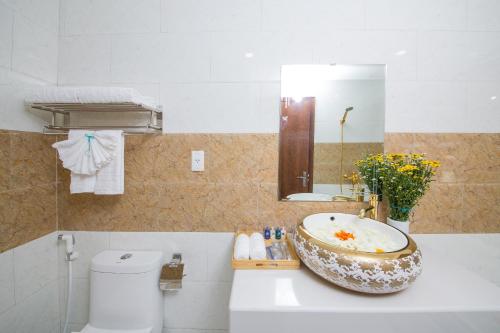 a bathroom with a sink and a toilet and a mirror at Pariat River Front Hotel in Da Nang