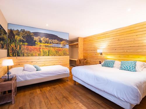 two beds in a room with a large painting on the wall at Le Relais des Lacs Bourgogne Morvan in Planchez