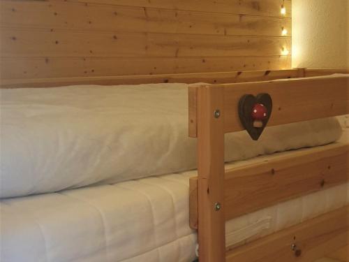 - un lit avec une tête de lit en bois et un cœur dans l'établissement Studio rénové 3/4 pers · Balcon Sud · Ski aux pieds - FR-1-181-2580, à Aime La Plagne