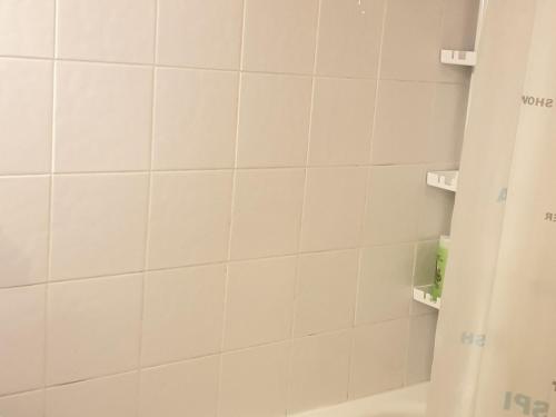 La salle de bains est pourvue de murs carrelés blancs et d'une douche. dans l'établissement Studio rénové 3/4 pers · Balcon Sud · Ski aux pieds - FR-1-181-2580, à Aime La Plagne