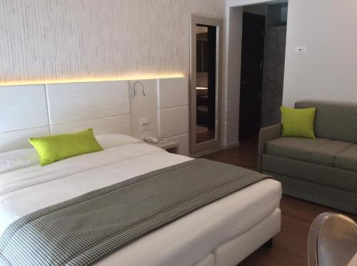 a bedroom with a bed with green pillows and a chair at Hotel Ariston & Apartments in Varazze