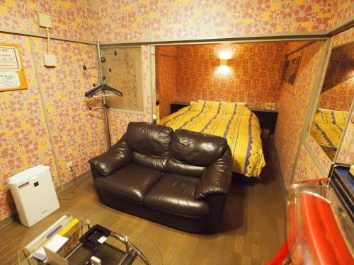 a bedroom with a leather couch in front of a bed at ホテルセーラ赤堀店 