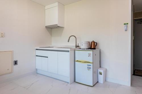 a white kitchen with a sink and a refrigerator at Aewol Oceanstay in Jeju