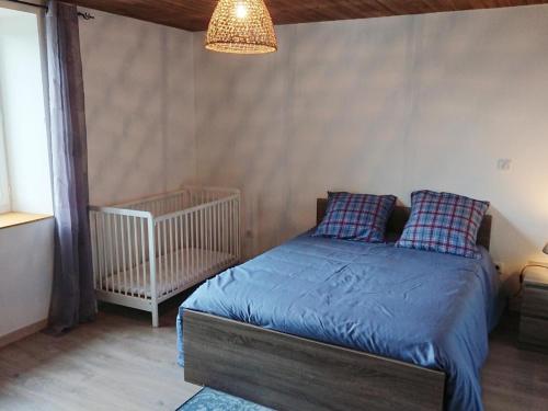 een slaapkamer met een bed met blauwe lakens en een wieg bij Gîte Oradour-Fanais, 4 pièces, 6 personnes - FR-1-653-133 in Oradour-Fanais