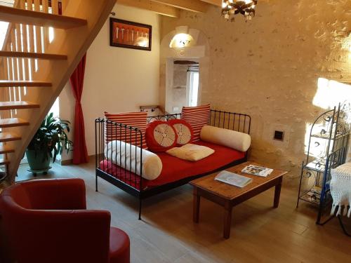 a living room with a red couch and a table at Gîte charentais avec cour privative, baby-équipement, télétravail, vélos, BBQ, animaux acceptés - FR-1-653-170 in Chalais