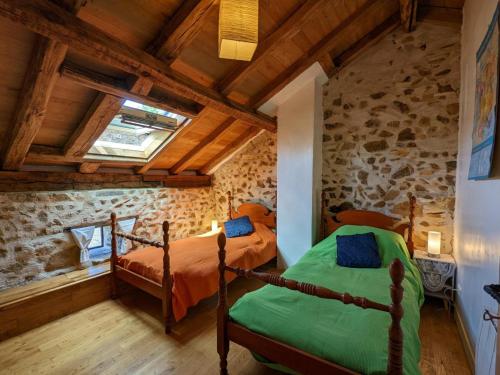 two beds in a room with a stone wall at Gîte Massignac, 4 pièces, 6 personnes - FR-1-653-213 in Massignac