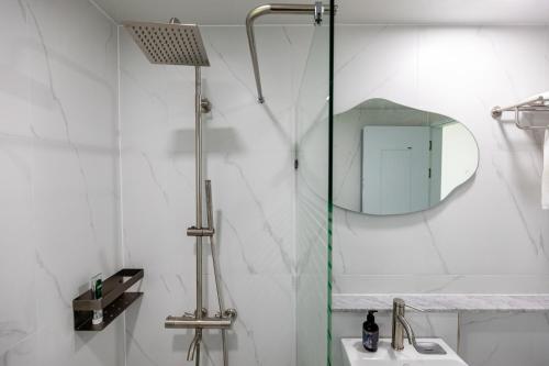 a bathroom with a shower and a sink and a mirror at Aewol Oceanstay in Jeju