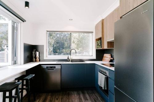 een keuken met blauwe kasten en een groot raam bij Farm & Sea Studio in Pyree
