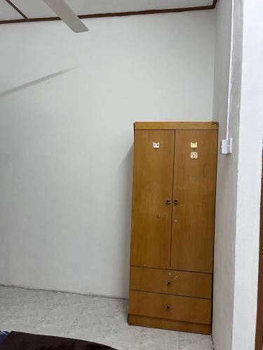 a wooden cabinet in a room with a wall at Roomstay Budget Kuala Terengganu Desa Chendering Private Bathroom in Kuala Terengganu