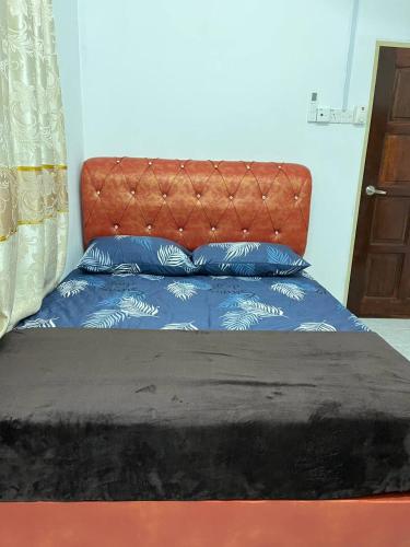 a bed with a orange headboard and two blue pillows at Roomstay Budget Kuala Terengganu Desa Chendering Private Bathroom in Kuala Terengganu