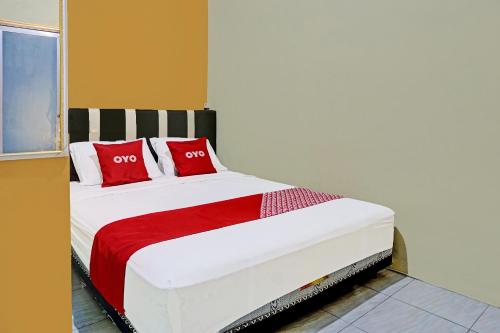 a bedroom with a bed with red pillows on it at OYO 91825 Ayu Lestari Homestay in Nganjuk