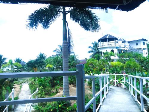 a balcony with a palm tree and a house at MG Chateau Resort in El Nido