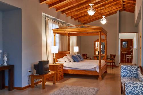 1 dormitorio con cama con dosel y TV en VillaBeatriz Lodge&Spa en Vilcabamba
