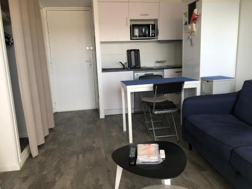 un salon avec un canapé bleu et une table dans l'établissement Appartement avec Balcon Proche des Thermes, Étang et Commerces - Climatisé, Animaux Admis - FR-1-503-134, à Balaruc-les-Bains