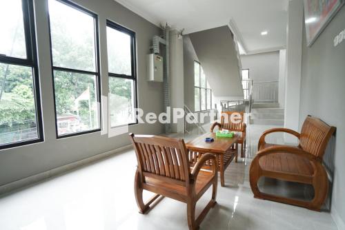 a dining room with a table and chairs and windows at Roemah Tebet Mitra RedDoorz in Jakarta