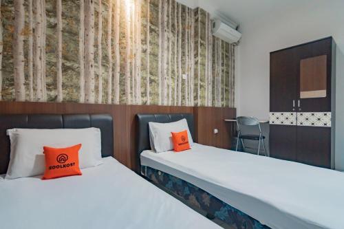 Duas camas com almofadas laranja num quarto em KoolKost near Cihampelas Walk em Bandung