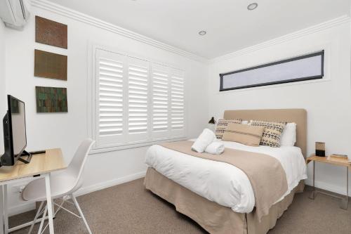 a bedroom with a bed and a desk and a television at Araluen House Werri Beach Gerringong in Gerringong