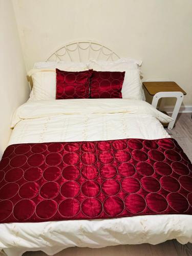 a white bed with red pillows and a red blanket at Double Bedroom in West Yorkshire, Leeds in Hunslet