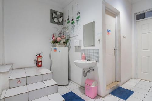 a white bathroom with a sink and a refrigerator at KoolKost near Cihampelas Walk in Bandung