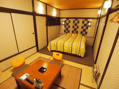 a small room with a bed and a table and chairs at ホテルセーラ赤堀店 