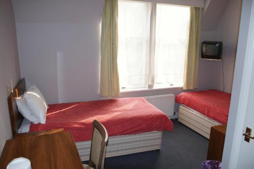 クロイドンにあるKirkdale Hotelのベッド2台と窓が備わる小さな客室です。