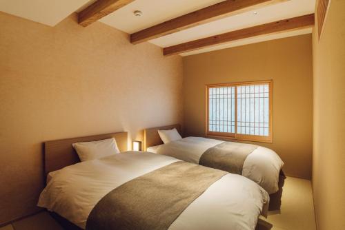 two beds in a room with a window at Yuhi House Kyoto Dog Friendly in Kyoto
