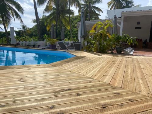 a wooden deck next to a swimming pool at Le M Hotel Marie Galante in Beauregard