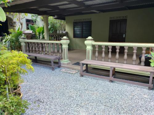 two benches sitting in front of a house at Hidden Homestay in Marang